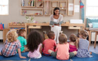 Teacher At Montessori School Reading To Children